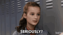 a girl sitting in front of lockers says seriously