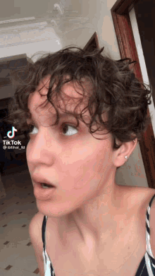 a woman with short curly hair has a tiktok app on her phone