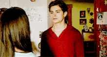 a man wearing a pearl necklace stands next to a woman in a room