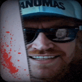 a man wearing sunglasses and a hat that says ' anomas ' on it
