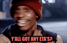 a man wearing a red beanie is smiling and says y all got any eta 's