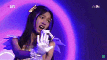 a woman is singing into a microphone in front of a purple background that says live on the bottom