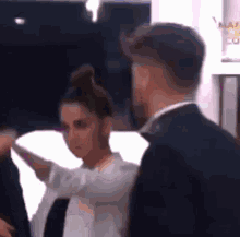 a man in a suit and tie is standing next to a woman in a bun .