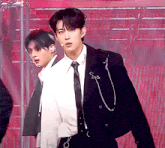 a man in a suit and tie stands next to a man in a white shirt