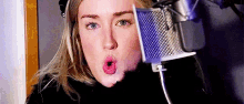 a woman is singing into a microphone and making a funny face