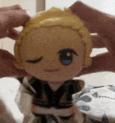 a stuffed doll with blonde hair and blue eyes is being held by a person