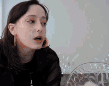 a woman wearing hoop earrings is sitting in front of a plate