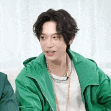 a man wearing a green jacket and a white shirt