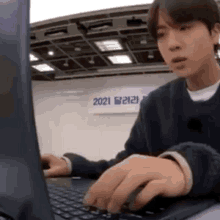 a man is typing on a laptop computer while sitting at a desk .