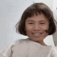 a woman with short brown hair is smiling and wearing a white shirt .