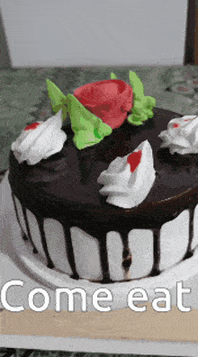 a chocolate cake with white frosting and a rose on top with the words come eat written below it