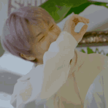 a close up of a person with purple hair making a heart with their hands .