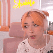 a woman with orange hair is wearing headphones and looking at the camera .