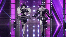 a couple of clowns are dancing on a stage with purple lights behind them