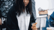 a girl in a black jacket is holding a cup of fries