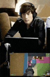 a man wearing headphones sits in front of a laptop