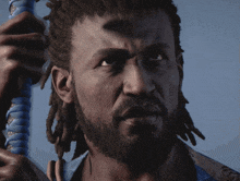 a man with dreadlocks and a beard holds a blue object in his hand