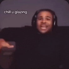 a man wearing headphones is pointing at the camera with his fingers .