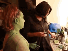 a woman with green face paint talks to another woman