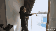 a woman is standing in front of a window with the words made in animatica on the bottom right