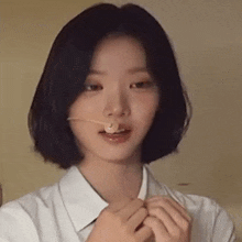 a young woman with short hair is eating a piece of food with a toothpick in her mouth .