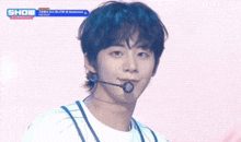 a young man wearing a microphone on a stage with the word show behind him