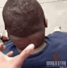 a person is touching the back of a man 's head while wearing a world star shirt