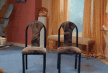 two chairs in a room with a window and a bench