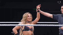 a woman in a wrestling ring is being congratulated by the referee