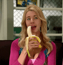a woman in a pink sweater eating a banana