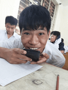a boy is smiling while looking at a cellphone