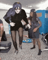 a woman in a black dress is dancing with a man in a black shirt behind her