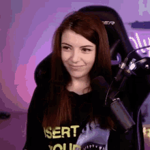 a woman is sitting in a chair with a microphone in front of her and smiling .