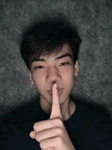 a young man is making a shhh sign with his finger