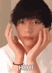 a young man is making a face with his hands on his face .