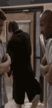 a group of young men are standing in a hallway talking to each other .