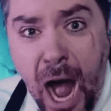 a man with a beard is making a funny face with his mouth wide open