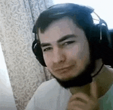 a man with a beard is wearing headphones and a microphone and making a funny face .