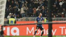 a soccer player is celebrating a goal in front of a sign that says rio money