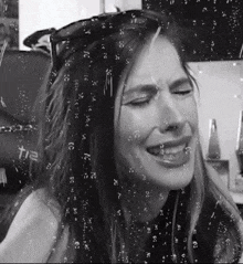 a black and white photo of a woman with tears coming out of her eyes behind a glass that says t12