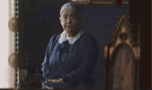 an older woman in a blue dress is standing in front of a mirror
