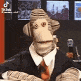 a puppet is wearing a suit and tie and is sitting at a table .