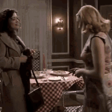 two women are standing in front of a table with plates and glasses on it