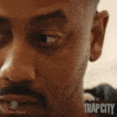 a close up of a man 's face with trap city written on the bottom right
