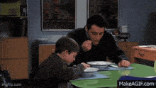 a man and a child are sitting at a table eating from bowls .