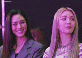 two women are sitting next to each other and one has a microphone on her neck .