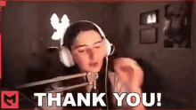 a woman wearing headphones is standing in front of a microphone saying `` thank you '' .