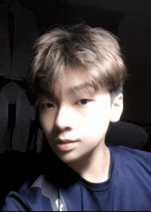 a young boy in a blue shirt is taking a selfie in the dark