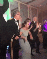 a man in a tuxedo is dancing with a woman in a grey dress