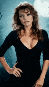 a woman in a black dress with a plunging neckline is standing in front of a full moon